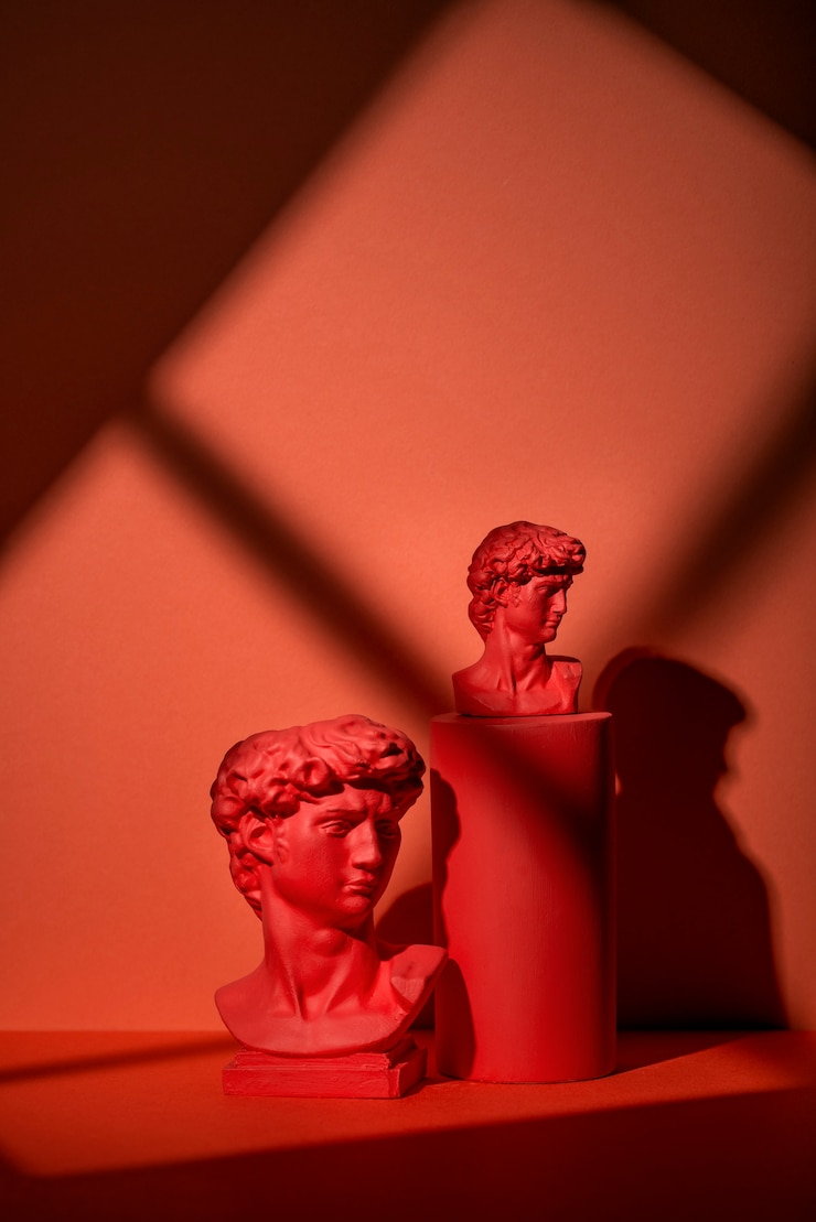 Foto grátis busto de gesso em fundo coral com formas geométricas