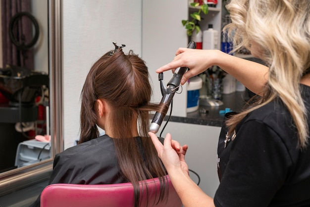 Cabeleireiro cuidando do cabelo de uma cliente no salão