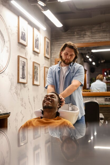 Cabeleireiro de tiro médio lavando o cabelo do homem