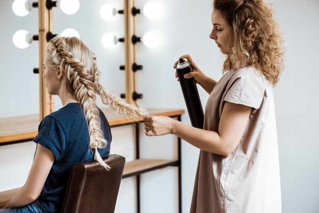 Cabeleireiro feminino fazendo penteado para mulher loira no salão de beleza