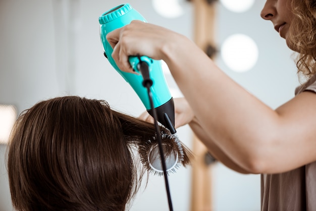 Foto grátis cabeleireiro feminino fazendo penteado para mulher morena no salão de beleza