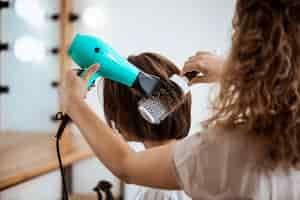 Foto grátis cabeleireiro feminino fazendo penteado para mulher morena no salão de beleza