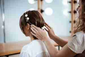 Foto grátis cabeleireiro feminino fazendo penteado para mulher morena no salão de beleza