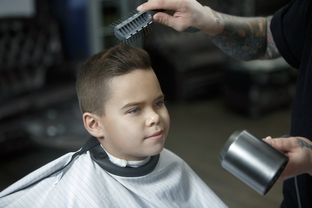 Cabeleireiro infantil cortando menino em uma barbearia