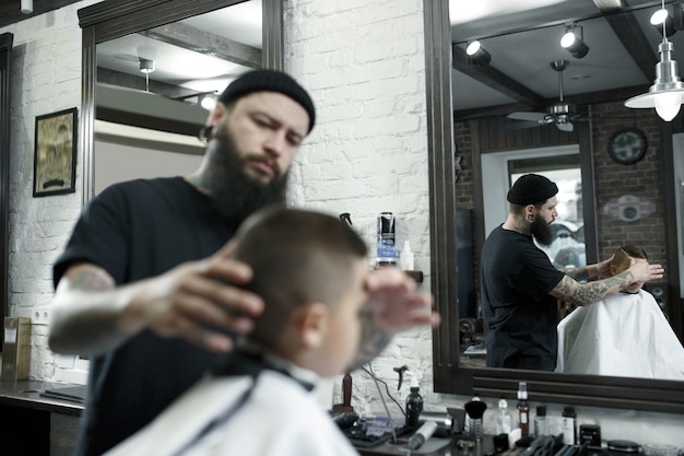 Cabeleireiro infantil cortando menino em uma barbearia