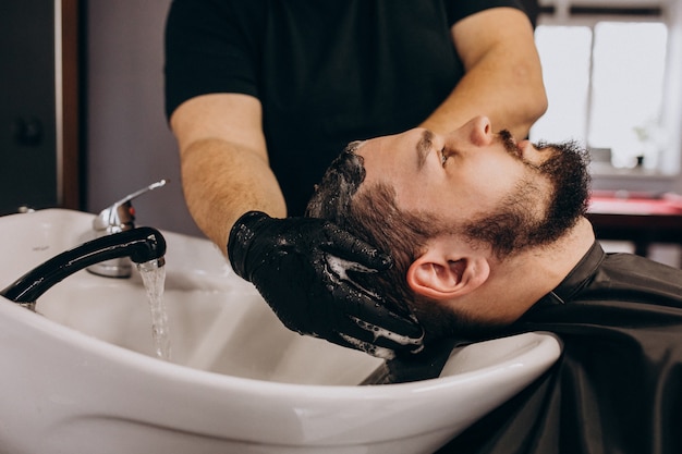 Cabeleireiro, lavando o cabelo de um cliente em uma barbearia