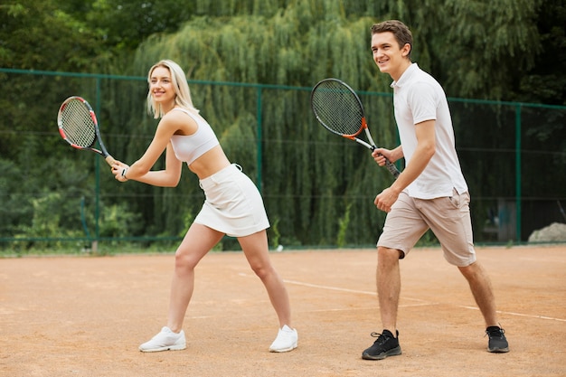 Caber jovem casal jogando tênis