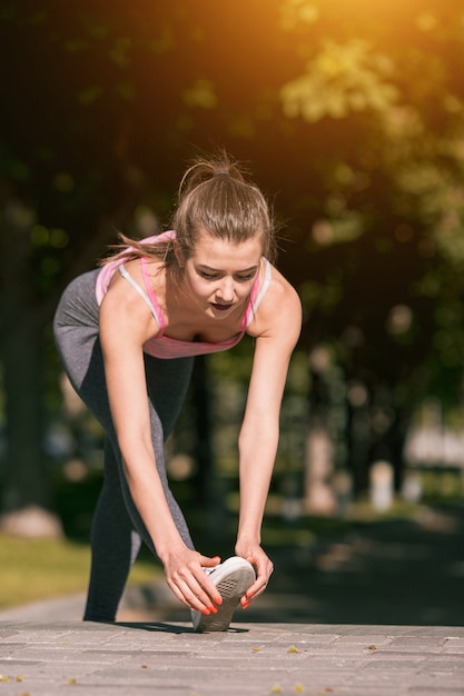 Caber mulher fitness fazendo exercícios de alongamento ao ar livre no parque
