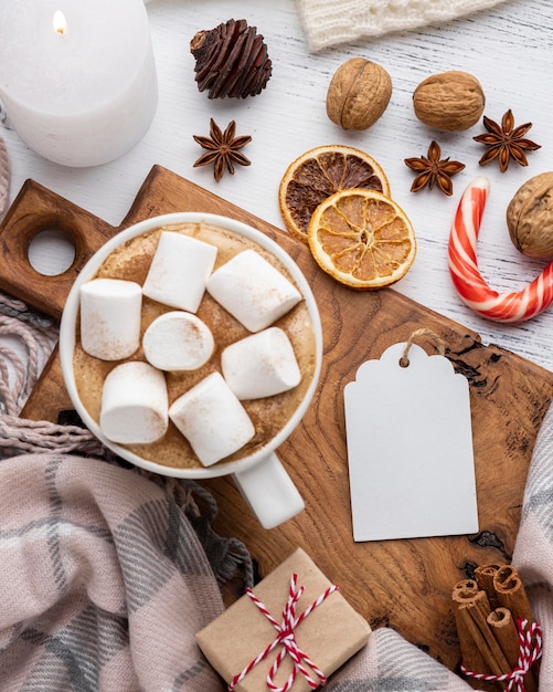 Cacau quente e marshmallows em xícara com vela e frutas cítricas secas