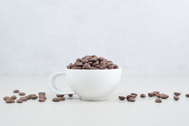 Cacho de grãos de café em caneca branca