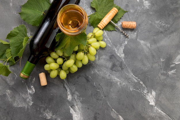 Cacho de uvas com garrafa de vinho no fundo de mármore