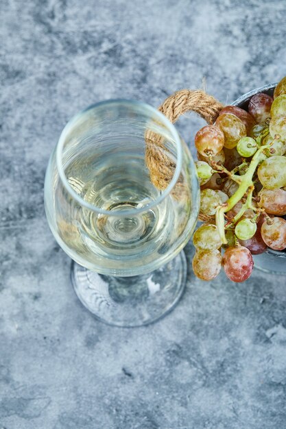 Cacho de uvas e uma taça de vinho no azul.