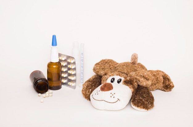 Cachorro de brinquedo macio para crianças com remédios e comprimidos ao lado. conceito de saúde e doenças infantis, proteção das crianças contra vírus.