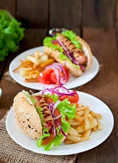 Cachorro-quente com ketchup mostarda e alface na mesa de madeira.