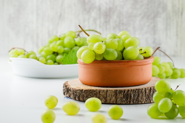 Cachos de uva com pedaço de madeira em placas na superfície branca