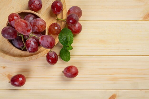 Cachos de uvas vermelhas maduras frescas na superfície de madeira.