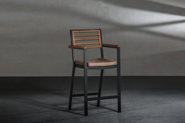 Cadeira simples com pernas altas metálicas em uma sala com paredes cinza