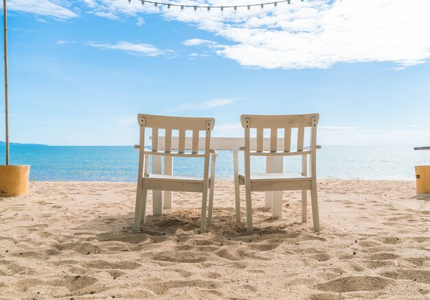 Cadeiras brancas e mesa na praia