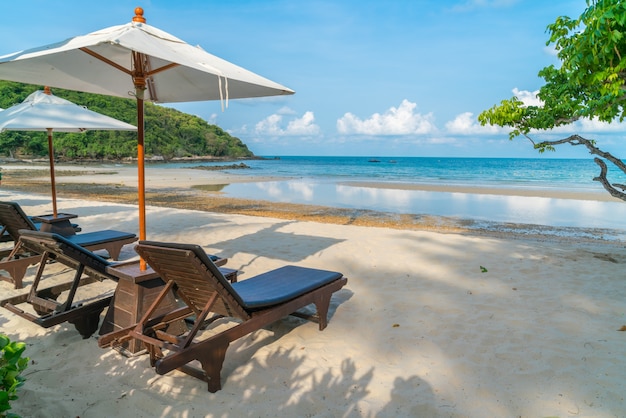 cadeiras de praia bonitas com guarda-chuva na pra areia branca tropical