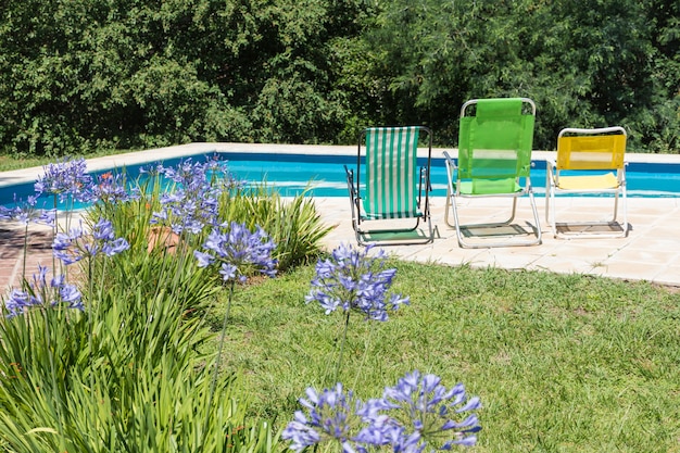 Cadeiras dobráveis perto da piscina e gramado no quintal