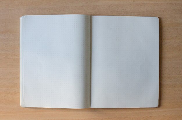 Caderno aberto em branco branco com muito espaço de texto em um fundo de madeira