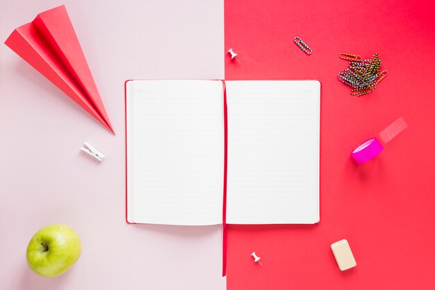 Caderno aberto em branco com vários itens de papelaria