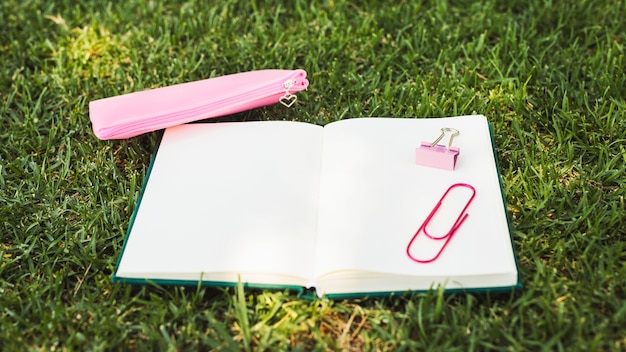 Caderno com artigos de papelaria rosa na grama