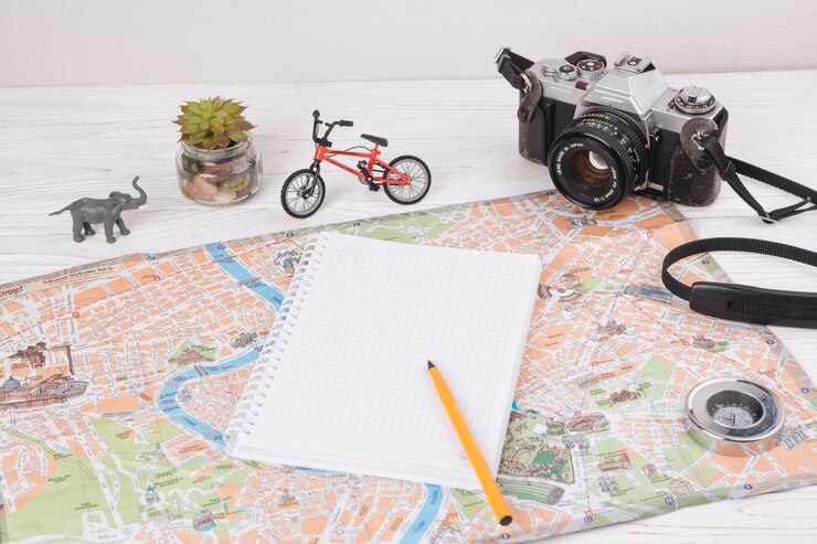 Foto grátis caderno com caneta no mapa perto de animal de brinquedo, câmera e bicicleta