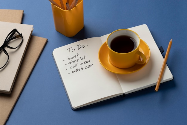 Foto grátis caderno com lista de tarefas na mesa com uma xícara de café ao lado