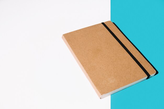 Caderno de capa marrom sobre fundo branco e azul