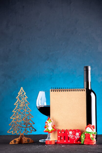 Caderno de decoração de natal de garrafa e copo de vinho com vista frontal sobre fundo azul claro