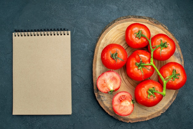 Caderno de madeira de tomate vermelho fresco com vista superior na mesa escura