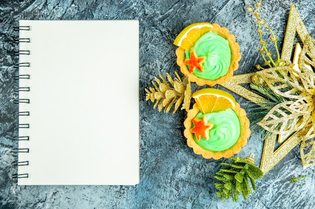 Foto grátis caderno de tortinhas pequenas com creme verde de enfeites de natal na mesa cinza