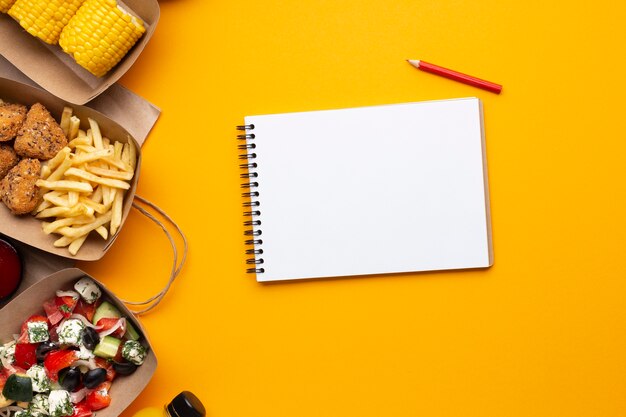 Caderno de vista superior com comida em fundo amarelo