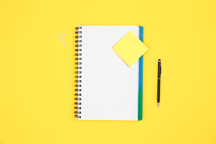Foto grátis caderno e lembrete de papel na vista superior do fundo amarelo