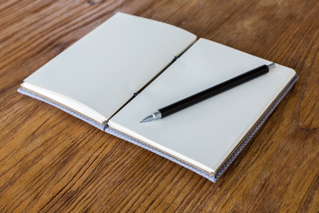 Caderno em branco com a pena na mesa de madeira
