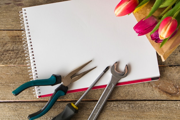 Caderno em branco com ferramentas e flores para o dia de pai