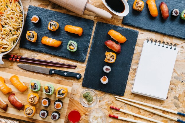Caderno em branco perto do conjunto de sushi