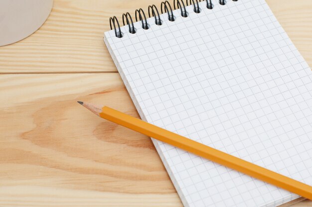 Caderno espiral em branco com o lápis deitado na mesa de madeira. Tabela de mesa home designer moderno com página em branco do bloco de notas