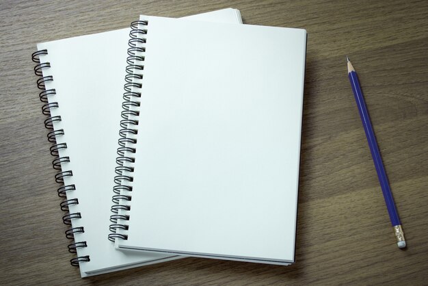 Caderno espiral em branco e lápis em fundo de madeira escura