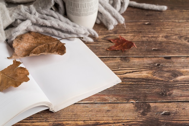 Caderno perto de folhas de outono e lenço na mesa