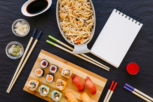 Caderno perto de sushi e macarrão