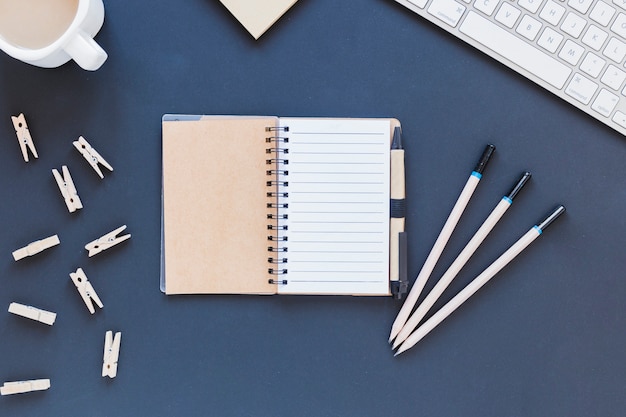 Foto grátis caderno vazio aberto perto de artigos de papelaria e teclado