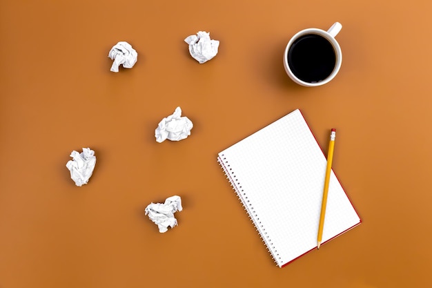 Foto grátis caderno vazio com xícara de café e bolas de papel amassadas planas