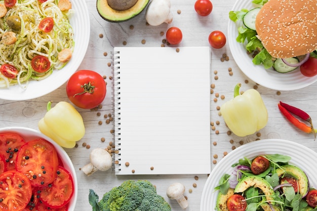 Caderno vazio rodeado por comida vegetariana deliciosa