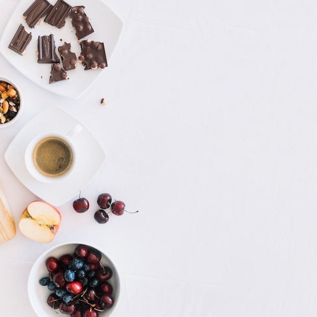 Café com dryfruit; pedaços de chocolate e frutas no pano de fundo branco