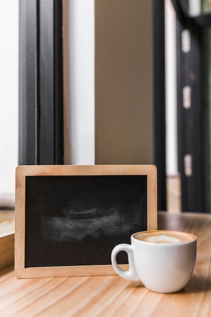 Café com leite com ardósia preta na mesa de madeira