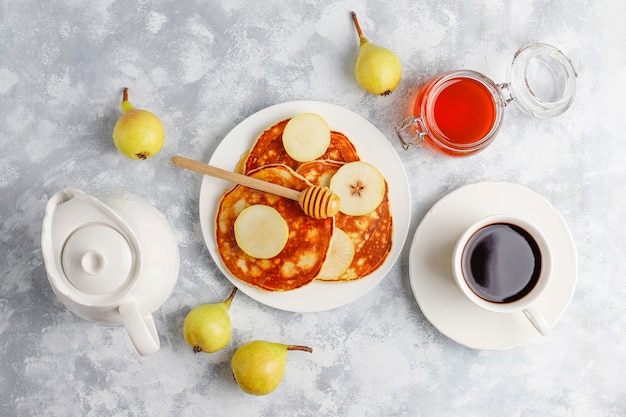 Café da manhã caseiro: panquecas de estilo americano, servidas com peras e mel com uma xícara de chá no concreto. vista superior e cópia