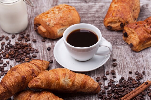 Café da manhã com coissants frescos com café e leite na mesa de madeira rústica. Croissant dourado.