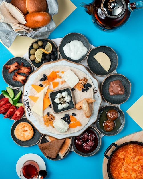 Foto grátis café da manhã com queijo e frutas secas no prato preto azeitonas verdes creme figo e geléia de morango